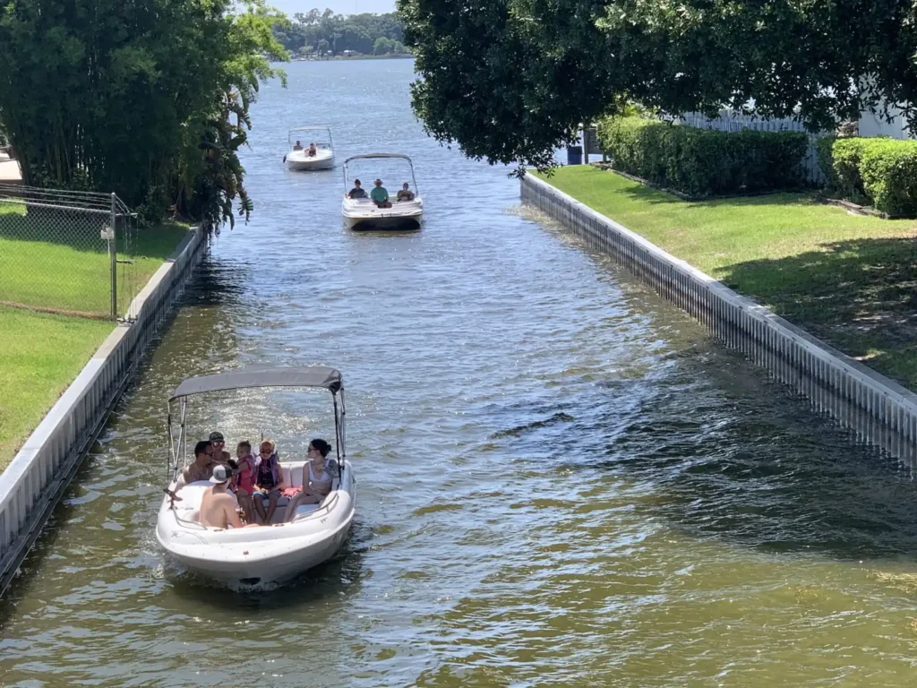 Three boats travelling through a seawalled canal between two lakes
